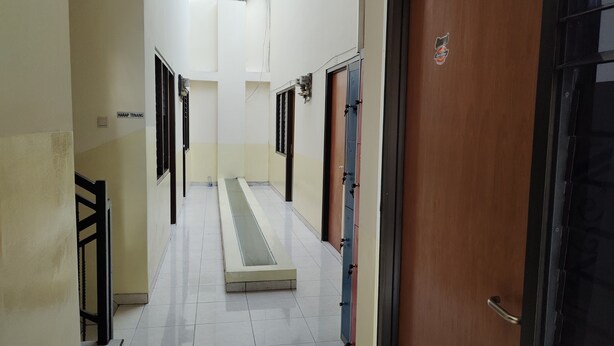 A hallway with a central walkway, doors on both sides, and a sign reading "HAP RAP TENANG". - Hotel O C16 Siwalankerto Syariah (Sidoarjo)