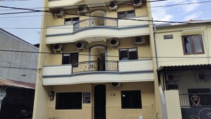 A multi-story building with balconies, air conditioning units, and a sign indicating a parking area. - Hotel O C16 Siwalankerto Syariah (Sidoarjo)