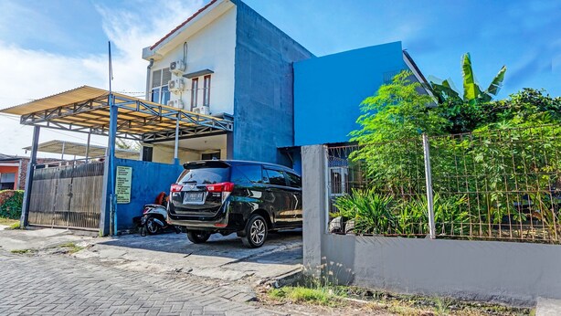 A modern building with a blue facade, a covered parking area, and a gated entrance. - OYO Life 91718 Kost Damai Syariah (Sidoarjo)