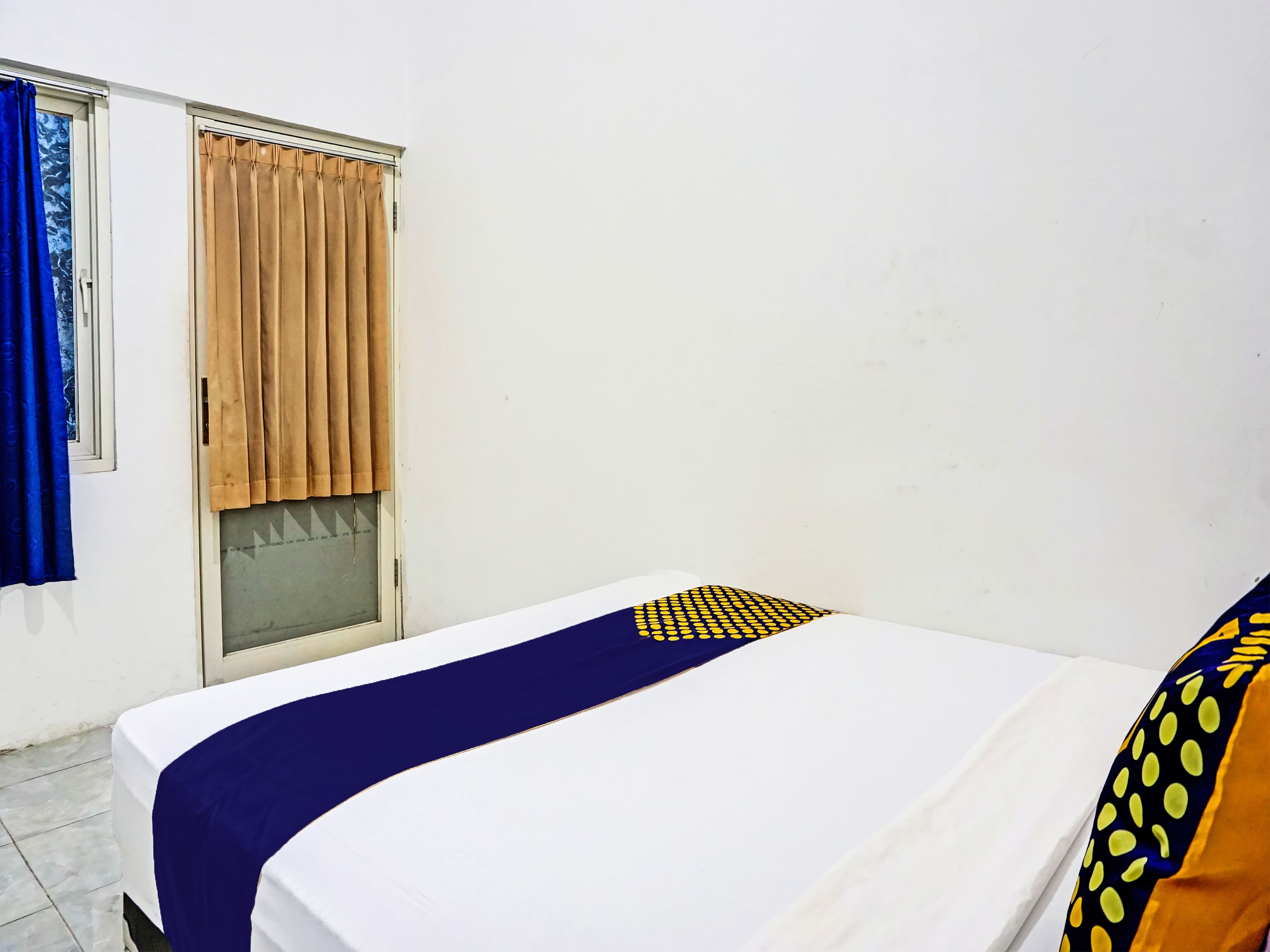 A room with a bed, a window with curtains, and a door.
