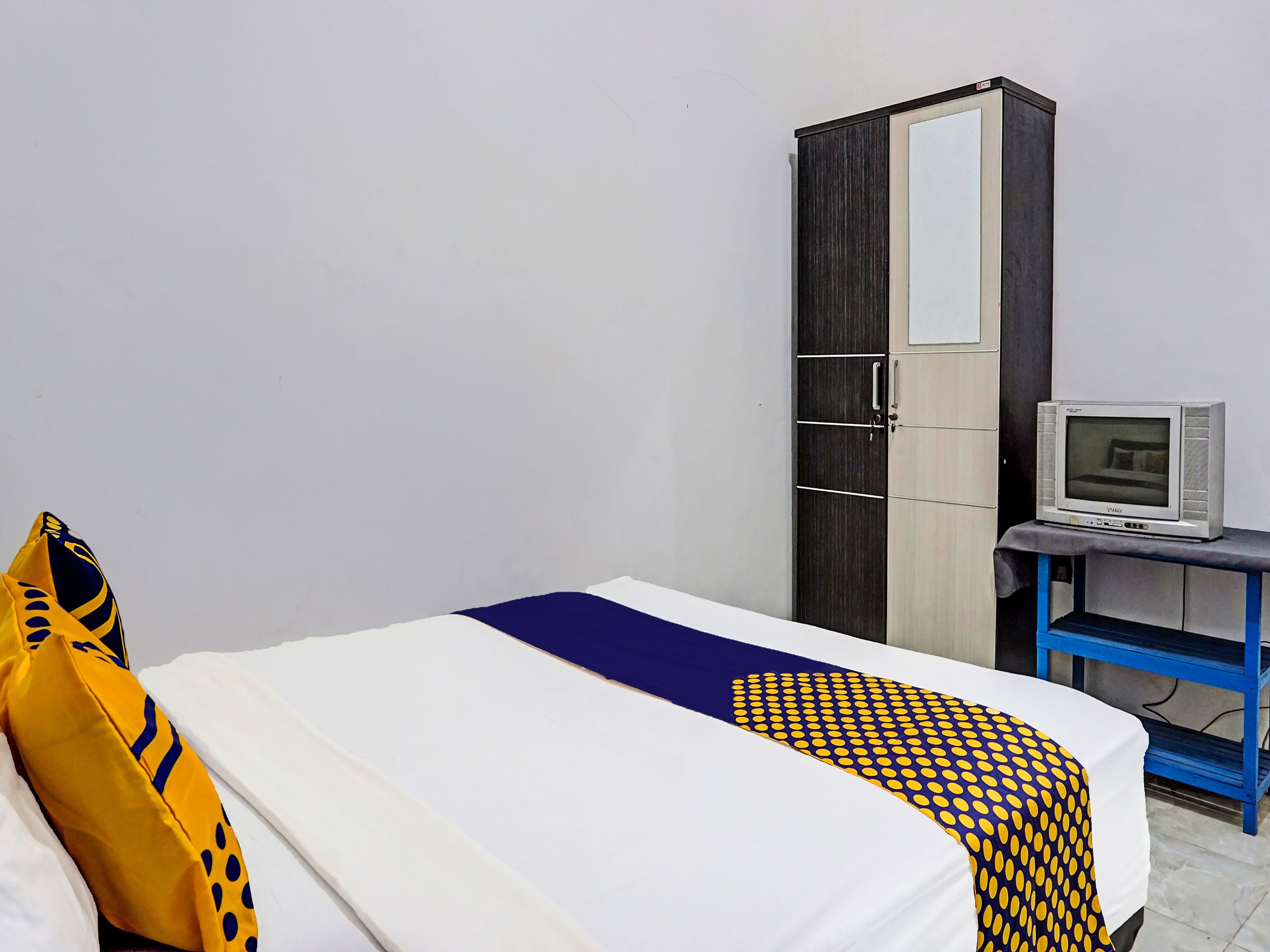 A hotel room with a bed, a wardrobe, and a television on a stand.