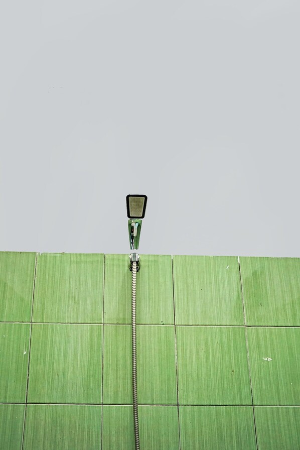 A shower head attached to a green tiled wall.