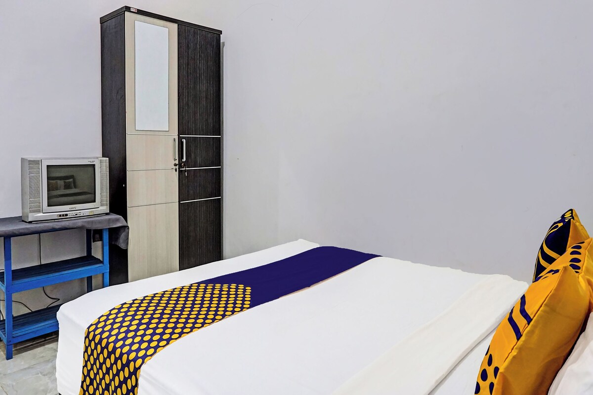 Une chambre à coucher avec un lit, une armoire, un bureau avec un ordinateur et une couverture à motifs.