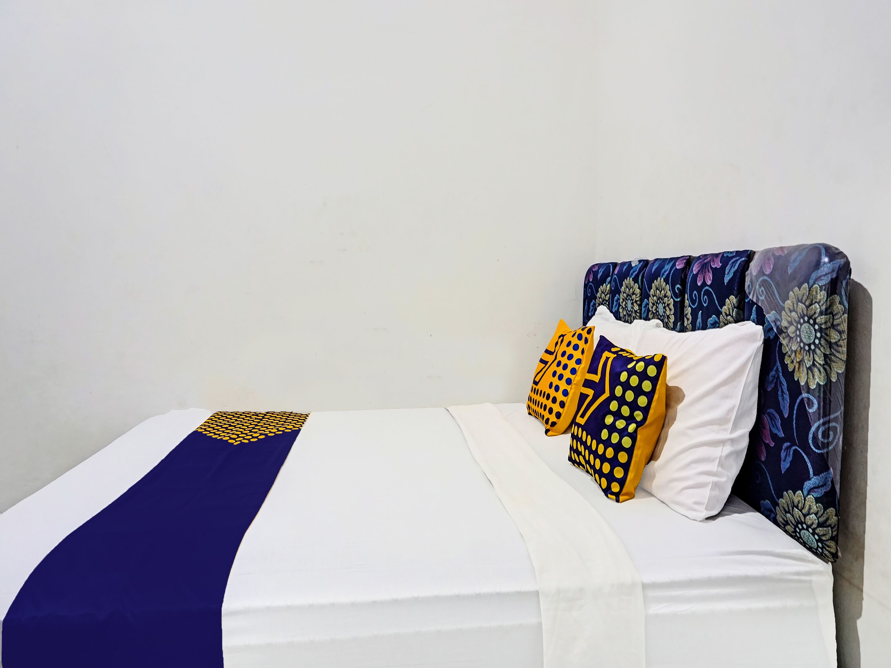 Een bed met een wit matras, een blauwe deken en gestreepte kussens.