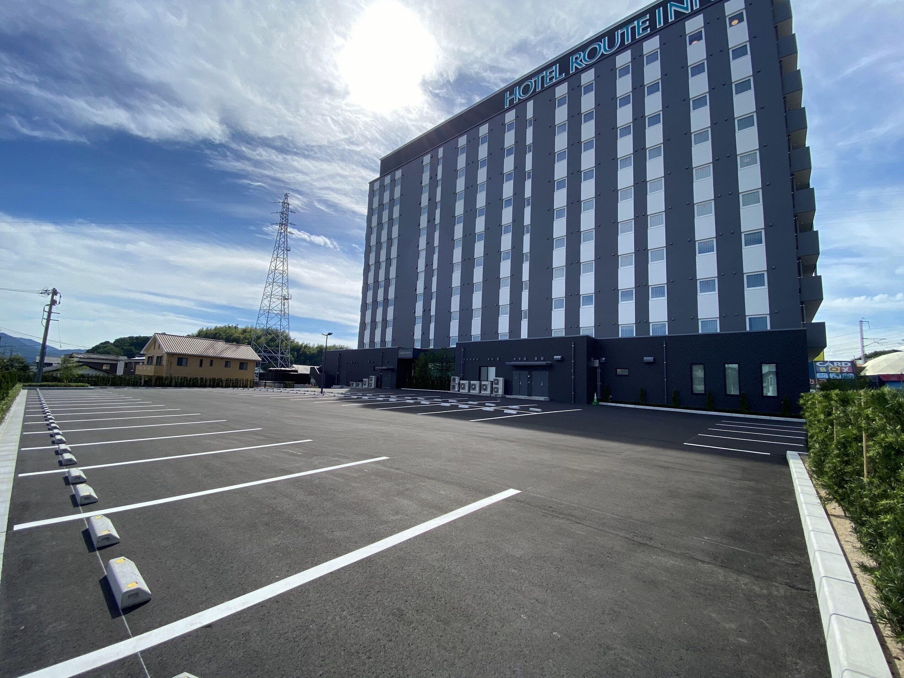 Un grande edificio di un albergo con un cartello che riporta la scritta "HOTEL ROUTE IN" e un parcheggio di fronte.