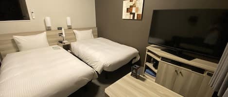 Une chambre d’hôtel avec deux lits, une télévision, un bureau et une armoire.