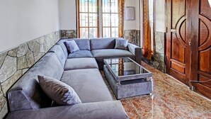 Una sala de estar moderna con un sofá modular gris, una mesa de centro de vidrio y una pared de acento de piedra.