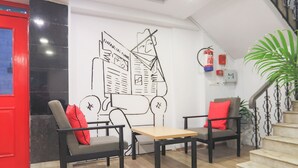 Un interior moderno con dos sillas negras con cojines rojos, una mesa de madera y una gran obra de arte abstracto en la pared.
