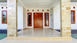 Un recibidor amplio con una puerta de madera flanqueada por pilares de piedra, que conduce a un suelo de baldosas.