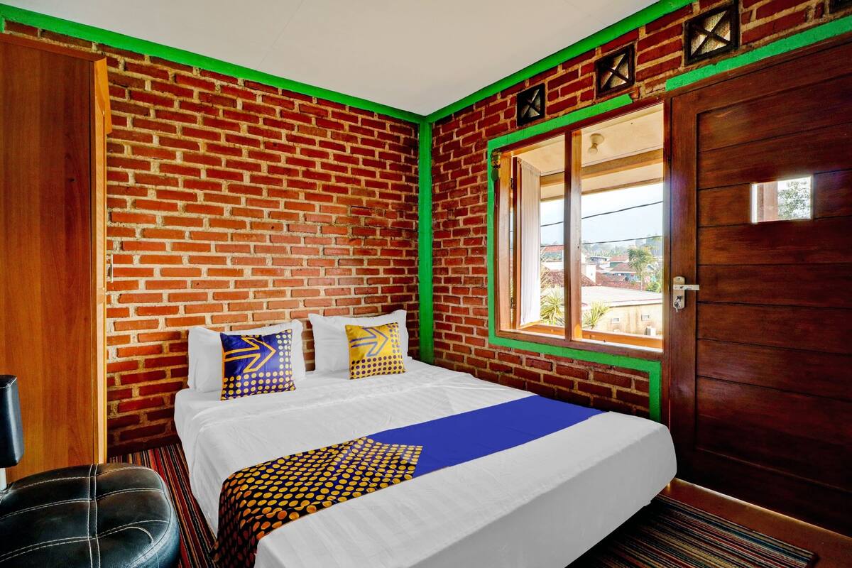 A hotel room with a brick wall, a wooden door, and a window with a view.