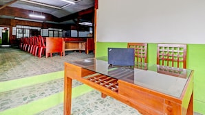 A conference room with a glass table, red chairs, and a green wall. - OYO Homes 90850 Cibeunying Eco Tourism Homestay Cibodas Maribaya 2 (Lembang)