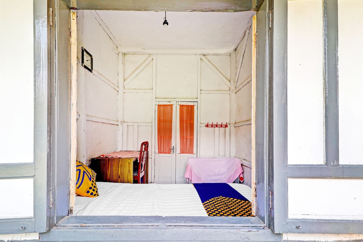 A room with a bed, a table, a chair, a clock, and a door.
