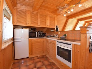 A compact kitchen with wooden cabinets, a refrigerator, a microwave, a coffee maker, and a stove. - Vacation home Alwin by Interhome (Suhl)