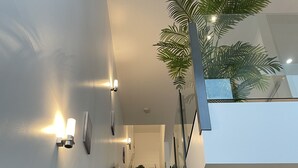 A modern staircase with glass railings, a potted plant, and wall-mounted lighting. - Luxury Penthouse Above the Shopping Town (Docklands)