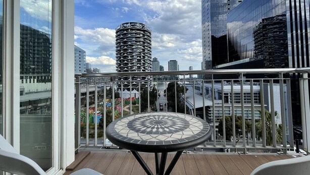 A balcony with a mosaic table, a view of a modern building, and a clear sky. - Luxury Penthouse Above the Shopping Town (Docklands)