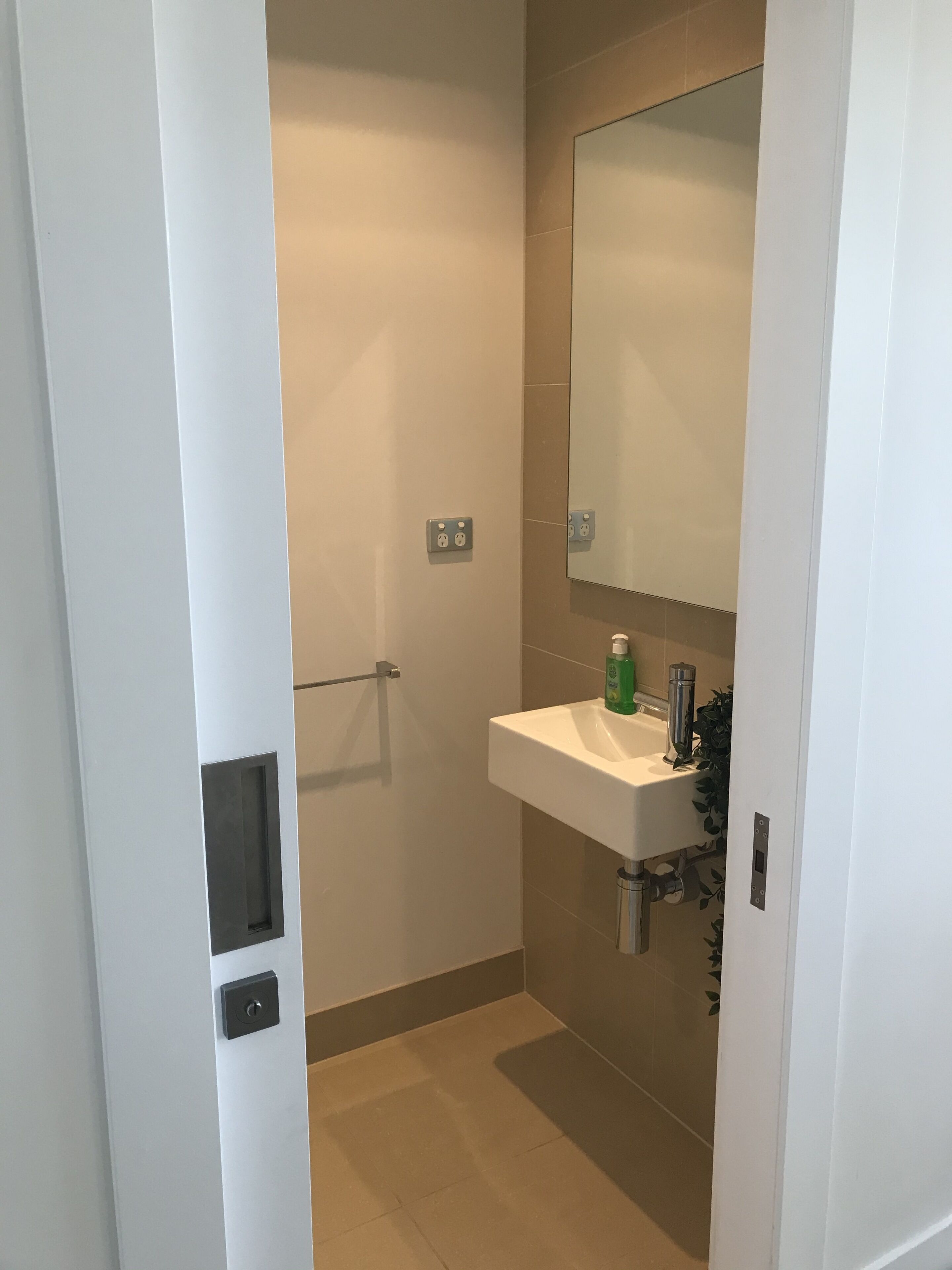 A bathroom with a white sink, a mirror, and a towel rack.