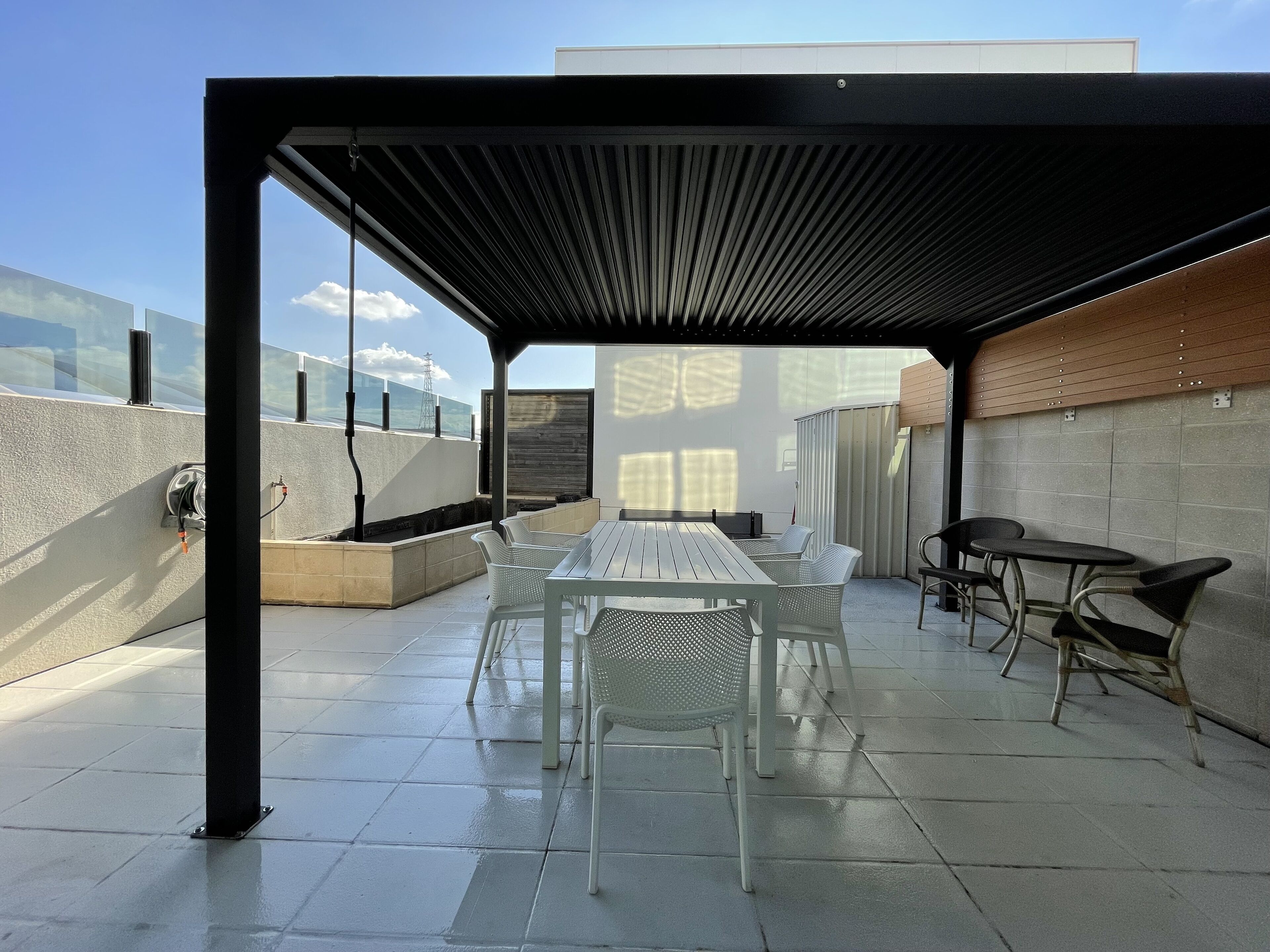 An outdoor patio with a table and chairs, a pergola, and a view of the city skyline.