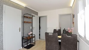 A modern dining area with a table and chairs, a decorative shelf, and a window with a view.