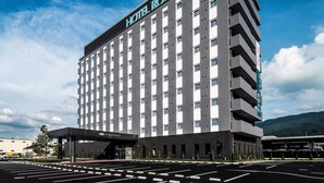 A modern hotel with a prominent sign reading "HOTEL ROUTE INN". It features a multi-story structure with a flat roof and a series of balconies. - Hotel Route Inn Shikoku Chuo - Mishimaka (Shikokuchuo)