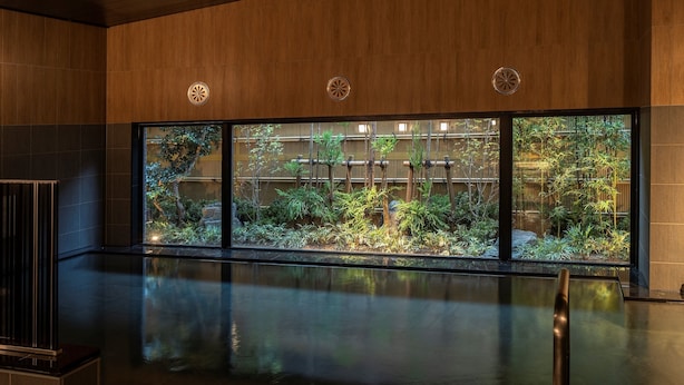 A modern indoor space with a reflective floor, large windows, and a view of a bamboo garden. - Hotel Route Inn Shikoku Chuo - Mishimaka (Shikokuchuo)