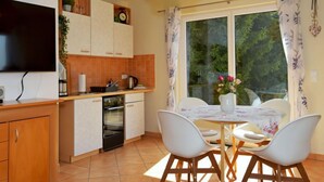 A modern kitchen with a flat-screen TV, wooden cabinets, and a dining area with a table and chairs. - Vacation home Konrad by Interhome (Suhl)
