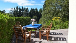 An outdoor patio with a table and chairs, surrounded by greenery and trees. - Vacation home Konrad by Interhome (Suhl)