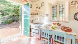 A kitchen with a gas stove, a sink, and a window overlooking a garden. - Villa Birdsong, among the Woods in Camaiore (Camaiore)