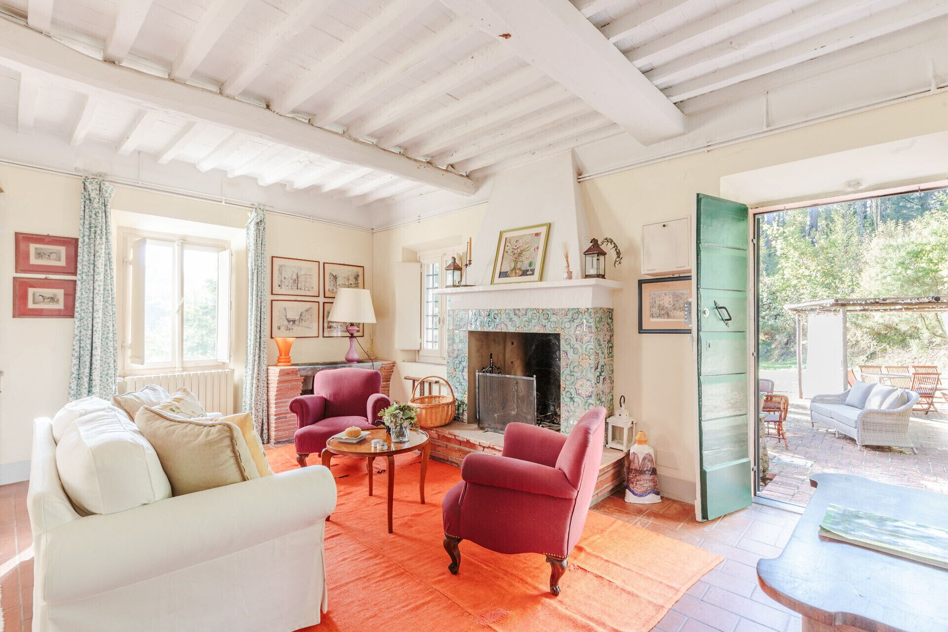 A spacious living room with a fireplace, a white sofa, a red armchair, and a dining table.