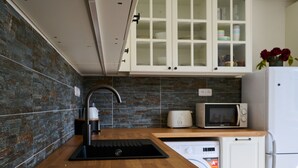 A modern kitchen with a wooden countertop, a sink, a microwave, and a refrigerator.