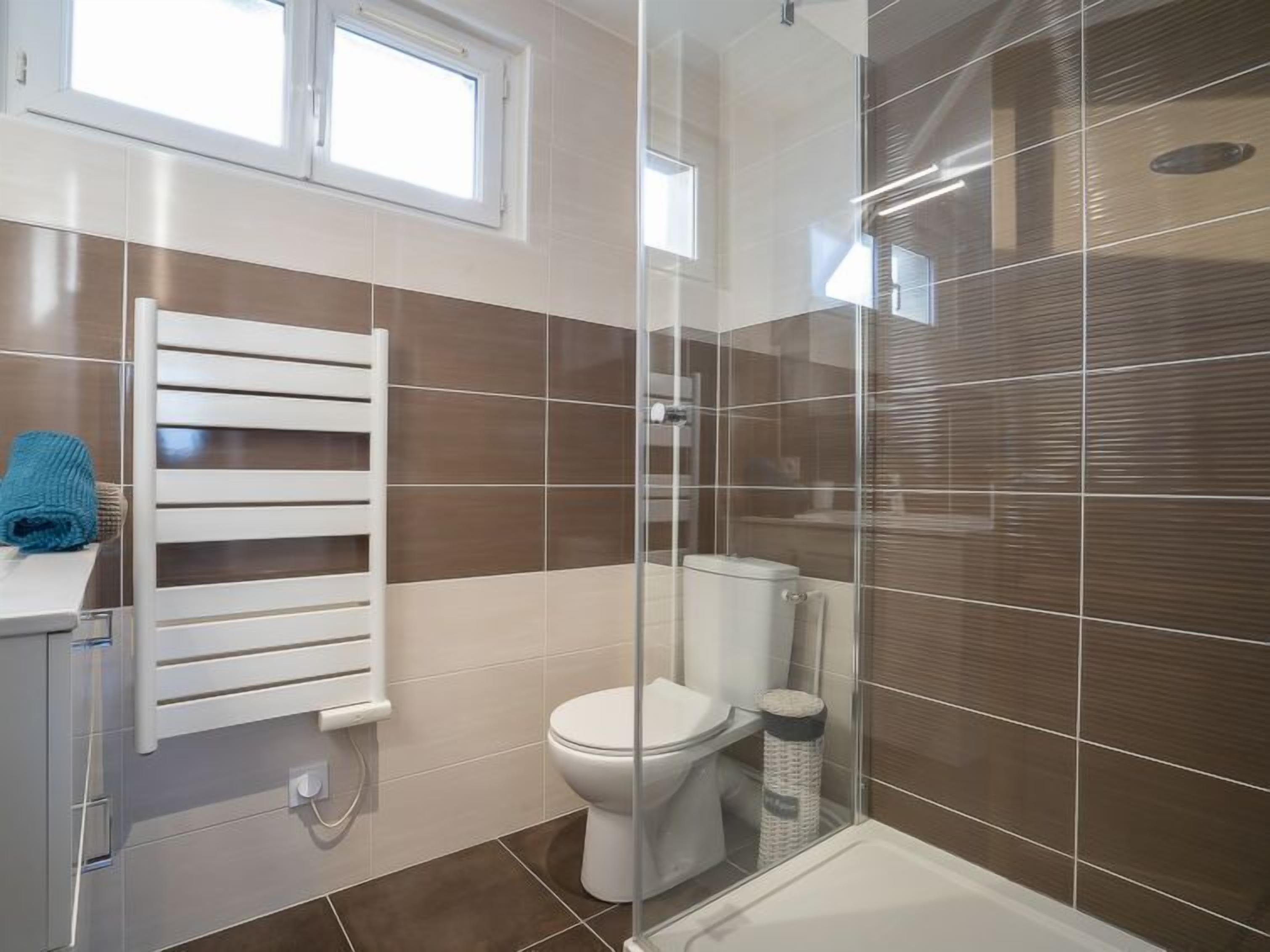 A modern bathroom with a glass shower enclosure, a toilet, and a bathtub.