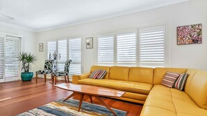 A living room with a yellow sofa, wooden coffee table, and striped rug. - Broke in the Vines - 6 bedroom farmhouse on working vineyard (Broke)