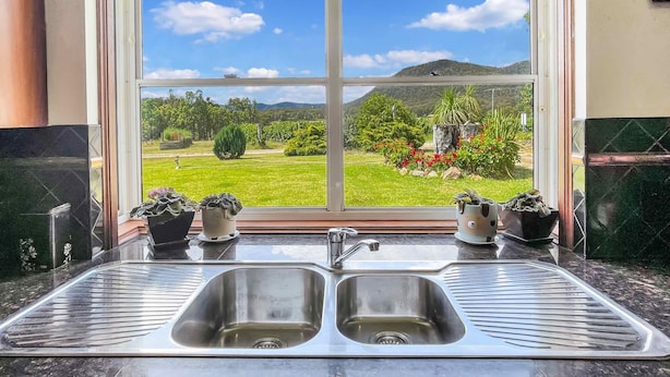 A kitchen with a large window offering a view of a green landscape and mountains. - Broke in the Vines - 6 bedroom farmhouse on working vineyard (Broke)