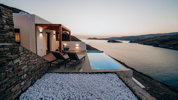 Una villa moderna con piscina, muros de piedra y vistas al mar.