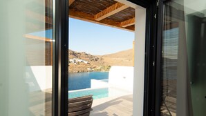Vista desde un balcón con piscina, que domina un paisaje costero con edificios blancos y un cielo azul despejado.