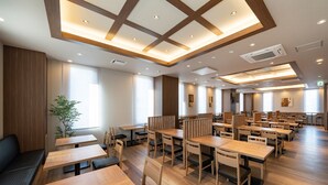 Een ruim restaurant met houten tafels en stoelen, grote ramen en een modern plafond.