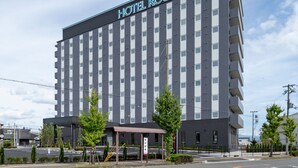 Een hotel met meerdere verdiepingen, met een modern ontwerp, met een opvallend bord met de tekst 'HOTEL ROUTE INN' bovenaan.
