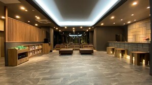Een hotel lobby met een modern design, met een centraal zitgedeelte, een receptiebalie en een groot raam dat natuurlijk licht biedt.