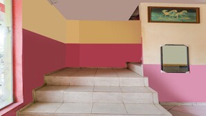 A staircase with beige steps leading to a landing, surrounded by walls painted in pink and yellow. - Hotel O Emes Jaya HomestayNearSamsung Electronic Indonesia PT (Batam)