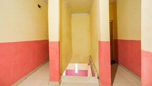 A narrow hallway with yellow and red walls, a tiled floor, and a visible door at the end. - Hotel O Emes Jaya HomestayNearSamsung Electronic Indonesia PT (Batam)