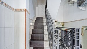Un escalier dont les marches sont recouvertes de carreaux blancs et foncés en alternance, une rampe en métal et des carreaux décoratifs le long des bords.