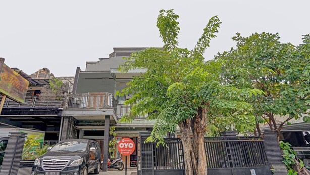 Un bâtiment moderne avec une entrée sécurisée par un portail, un arbre devant et une voiture garée.