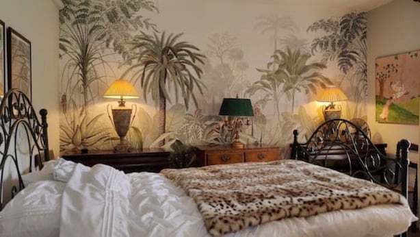 A bedroom with a bed, two nightstands, a cat, and a mural of palm trees. - Elegant Victorian house in South London. Excellent transport links. (London)