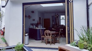A modern house with a large glass door leading to a dining area with a table and chairs. - Elegant Victorian house in South London. Excellent transport links. (London)