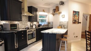 A modern kitchen with dark cabinetry, a built-in microwave, an oven, and a marble countertop. - Elegant Victorian house in South London. Excellent transport links. (London)