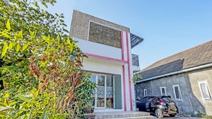 A modern two-story building with a flat roof, a large window, and a car parked in front. - OYO LIFE 91594 Bungah Residence Syariah (Gresik)