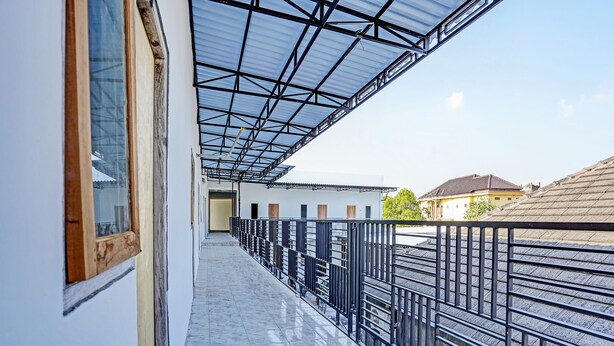 A corridor with a glass ceiling, metal railing, and a tiled floor. - OYO LIFE 91594 Bungah Residence Syariah (Gresik)