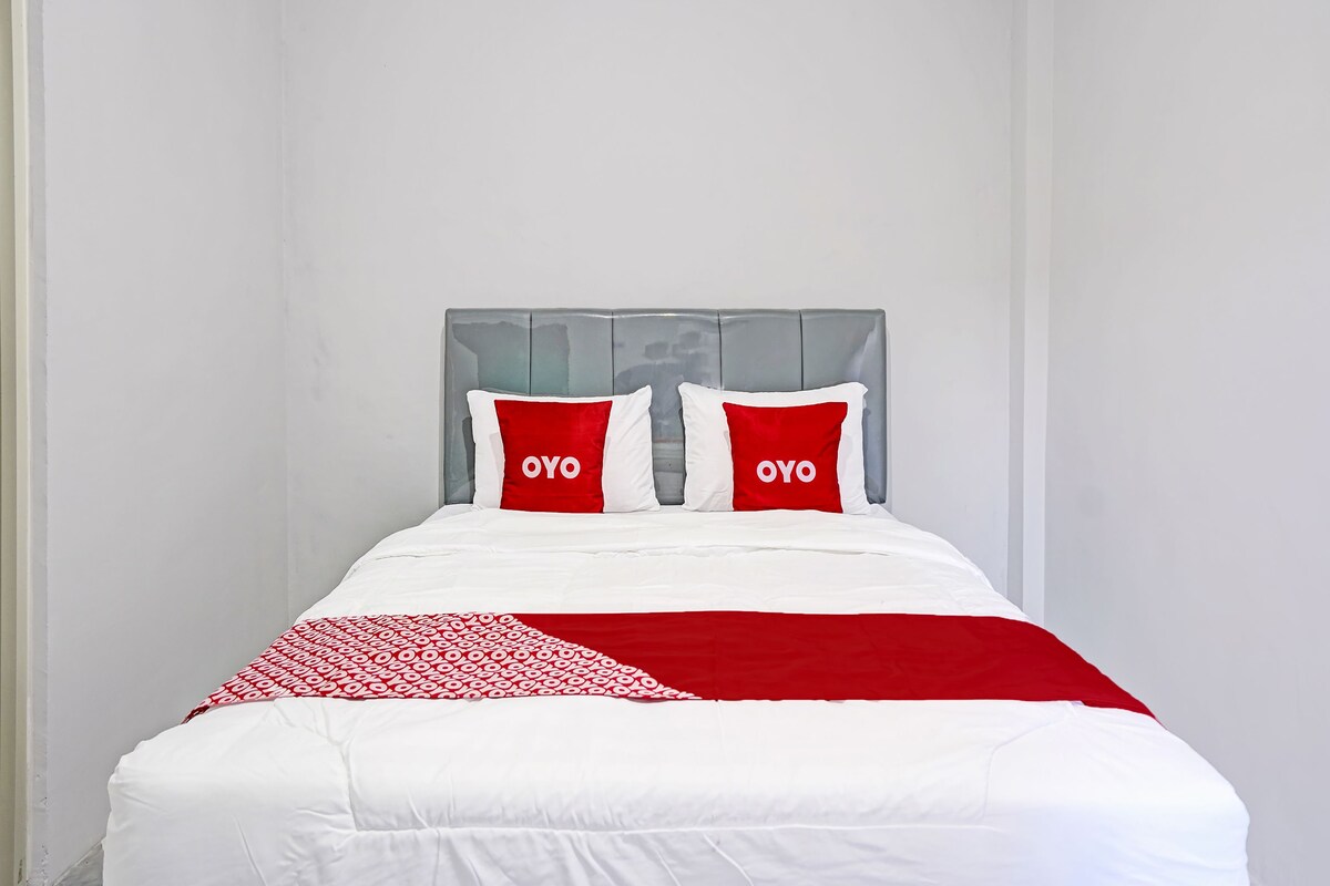 A bed with a white and red bedspread, two red pillows with 'OYO' text, and a grey headboard.
