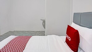 A hotel room with a bed, a red pillow, a grey headboard, and a white wall. - OYO LIFE 91594 Bungah Residence Syariah (Gresik)