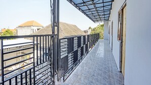 A covered balcony with a metal railing, a tiled floor, and a view of neighboring buildings. - OYO LIFE 91594 Bungah Residence Syariah (Gresik)