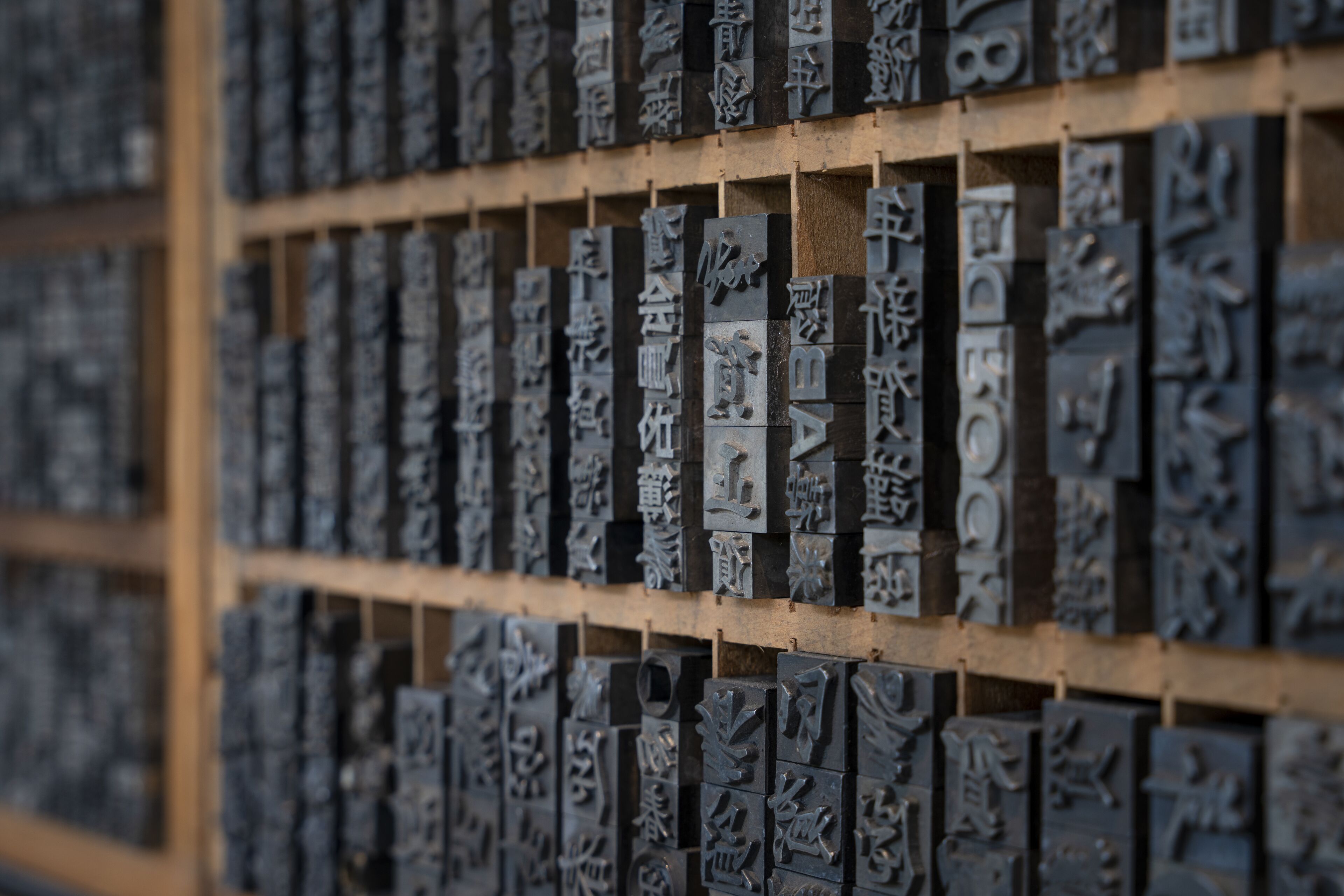 A collection of metal plaques with engraved text, likely used for identification or categorization, displayed on a wooden grid.